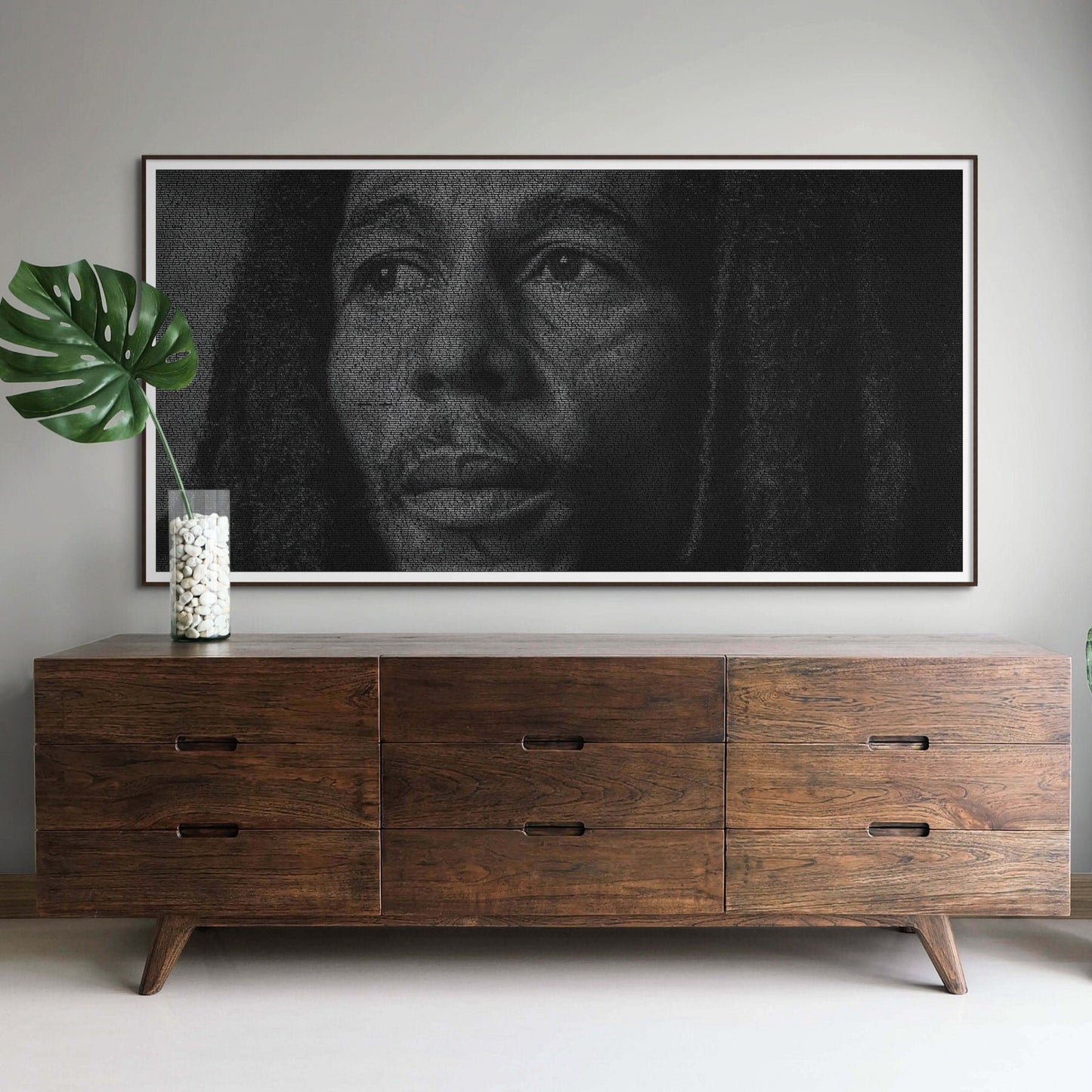 A black and white typographic portrait of Bob Marley, created from his song lyrics. Framed on a grey wall above a dresser.